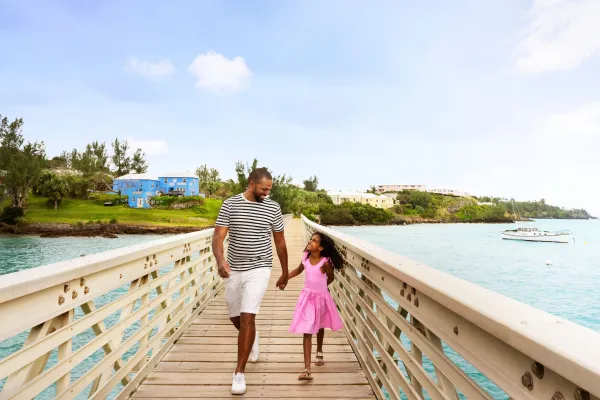 A father and daughter walking over a wood bridge looking at each other