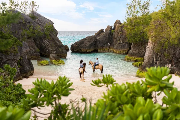 A couple riding horses on the beach