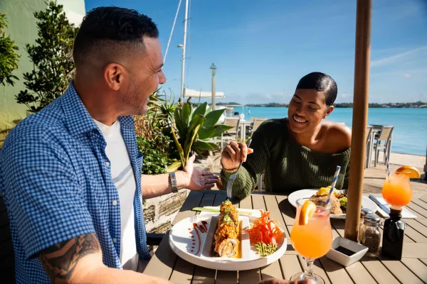 Two people enjoy some traditional Bermudian food on an outdoor patio in Bermuda