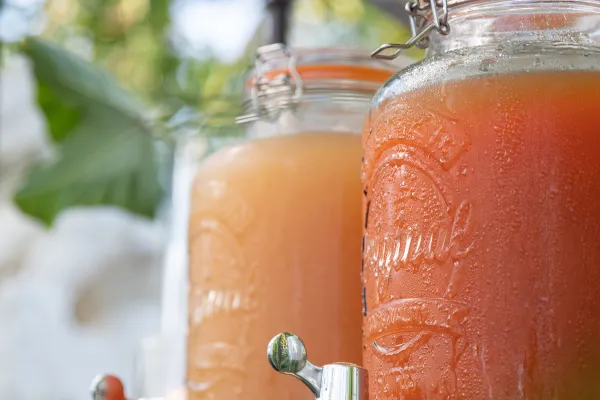 Two batches of rum punch cocktail in jugs with spigots