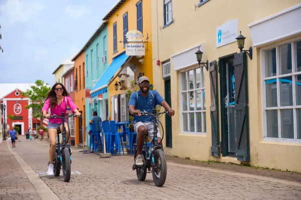 A couple rides electric bicycles through a Bermudian city