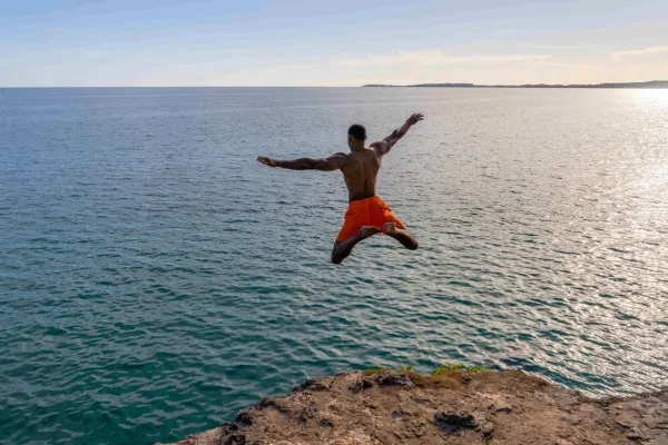 A man leaping off a cliff into the water below in Bermuda