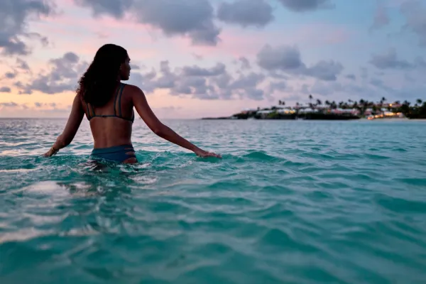 A woman wading in the ocean in Bermuda at dusk
