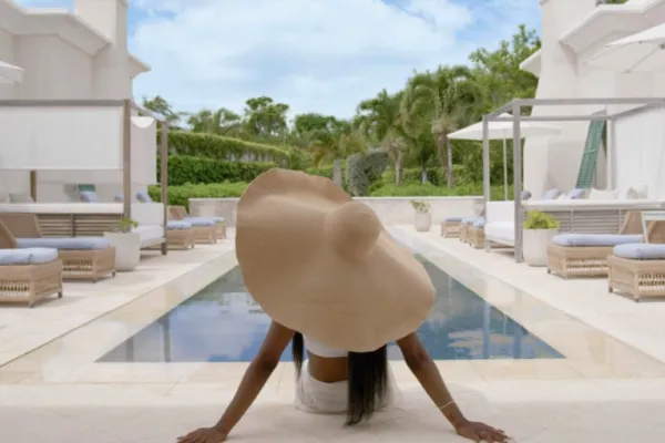 A woman in a large sun hat relaxes near a spa pool in Bermuda