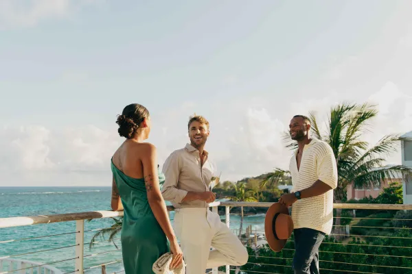 Three people relaxing at a beach balcony party overlooking the ocean in Bermuda