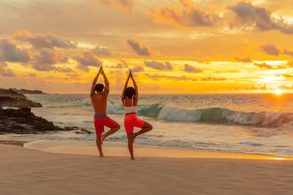 A couple doing yoga at sunrise on a beach in Bermuda