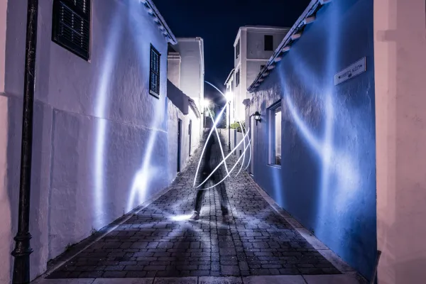 A person waves a light baton to cast beams of light in a Bermuda alleyway during an Art Walk at night