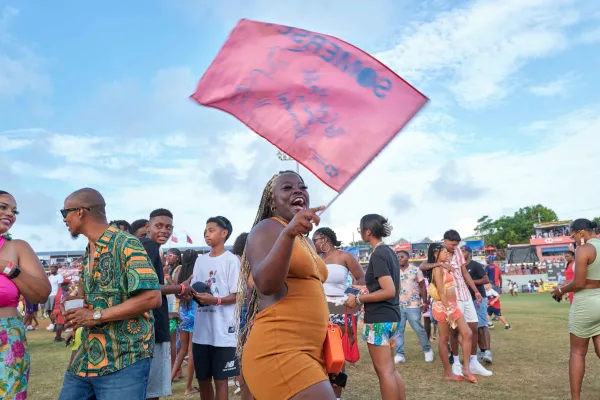 A woman smiling while waving a Somerset flag at Cup Match in Bermuda