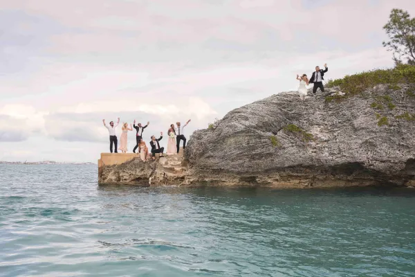 A bride and groom cliff jumping off the rocks with their friends in Bermuda