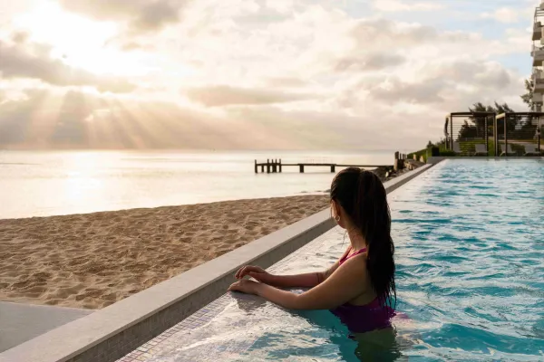A woman looks out on a Bermuda beach from a resort pool