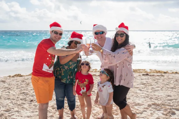 A family wearing Santa hats toasting their drinks on a Bermuda beach