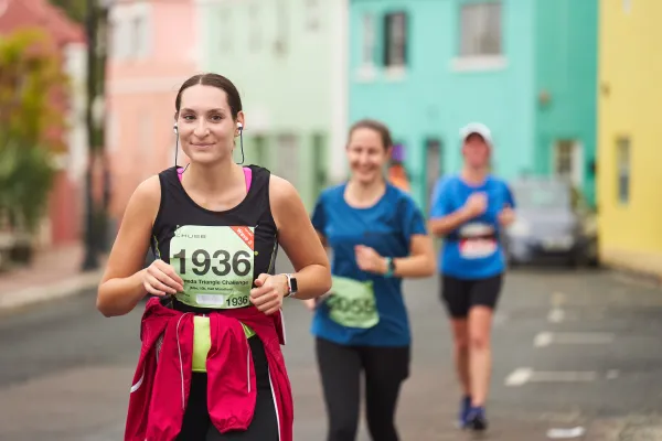 A woman is smiling while running a marathon.