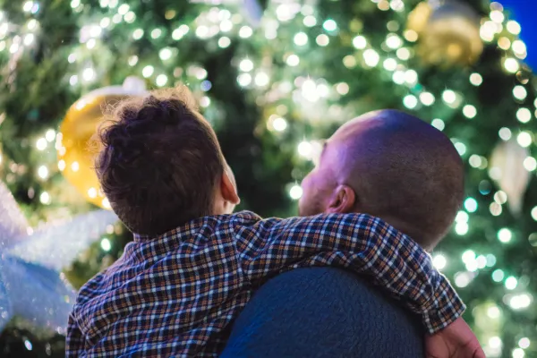 A father and son are posing by a christmas tree.