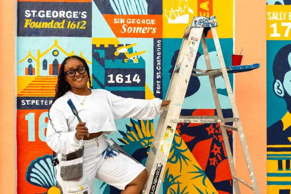 A woman is smiling at the camera with paint brushes.