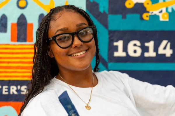 A woman is smiling at the camera with a paint brush.