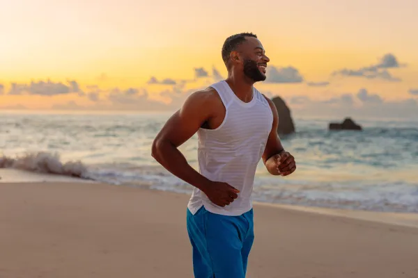 A man is running on the beach smiling.
