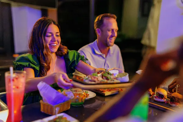 A woman is passing a plate of food around.