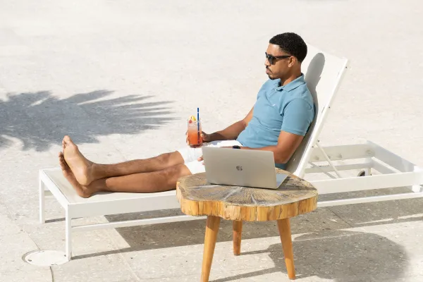 A man is sitting on a lounge chair by a lounge chat.