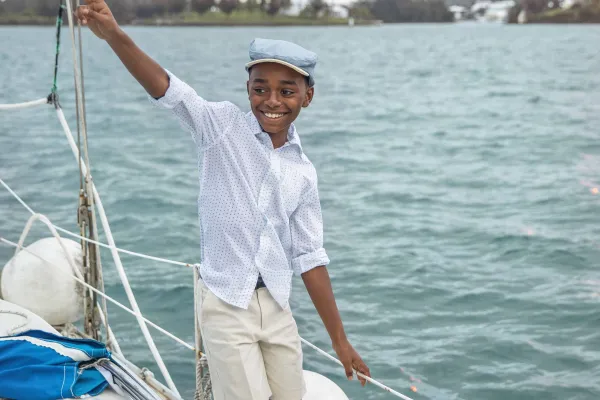 A little boy is smiling while walking on a boat.
