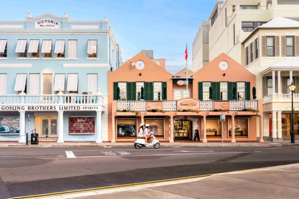 A couple is riding a scooter on colourful Front Street.