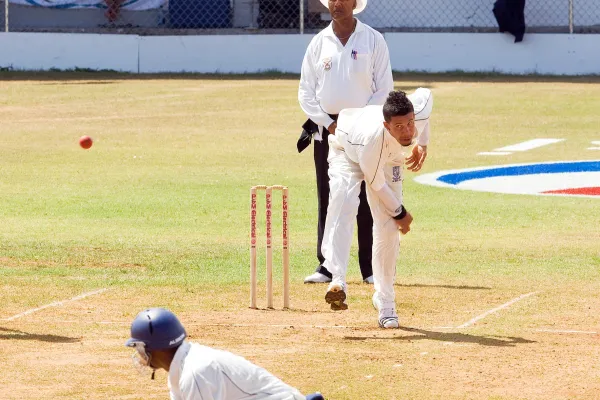 A man is bowling during a cricket game.