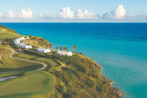 An aerial view of Port Royal Golf Course with a green fairway and blue, calm ocean. 