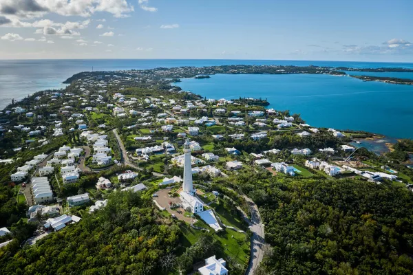 Aerial view of Gibbs Hill Lighthouse with calm waters and blue skies. 