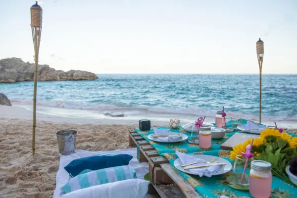 A luxe picnic table set up on the beach at dusk.