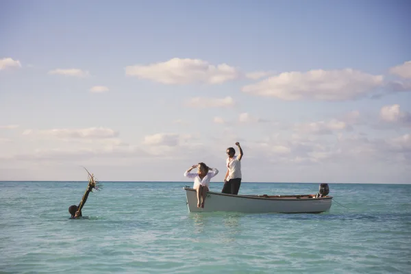 A man fishing for spiny lobster in Bermuda, a couple is cheering from the boat.