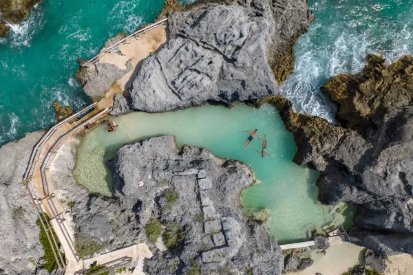 An aerial of people in a natural sea pool. 