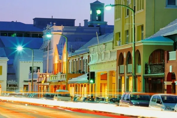 Street view at night with cars parked on the side of the road