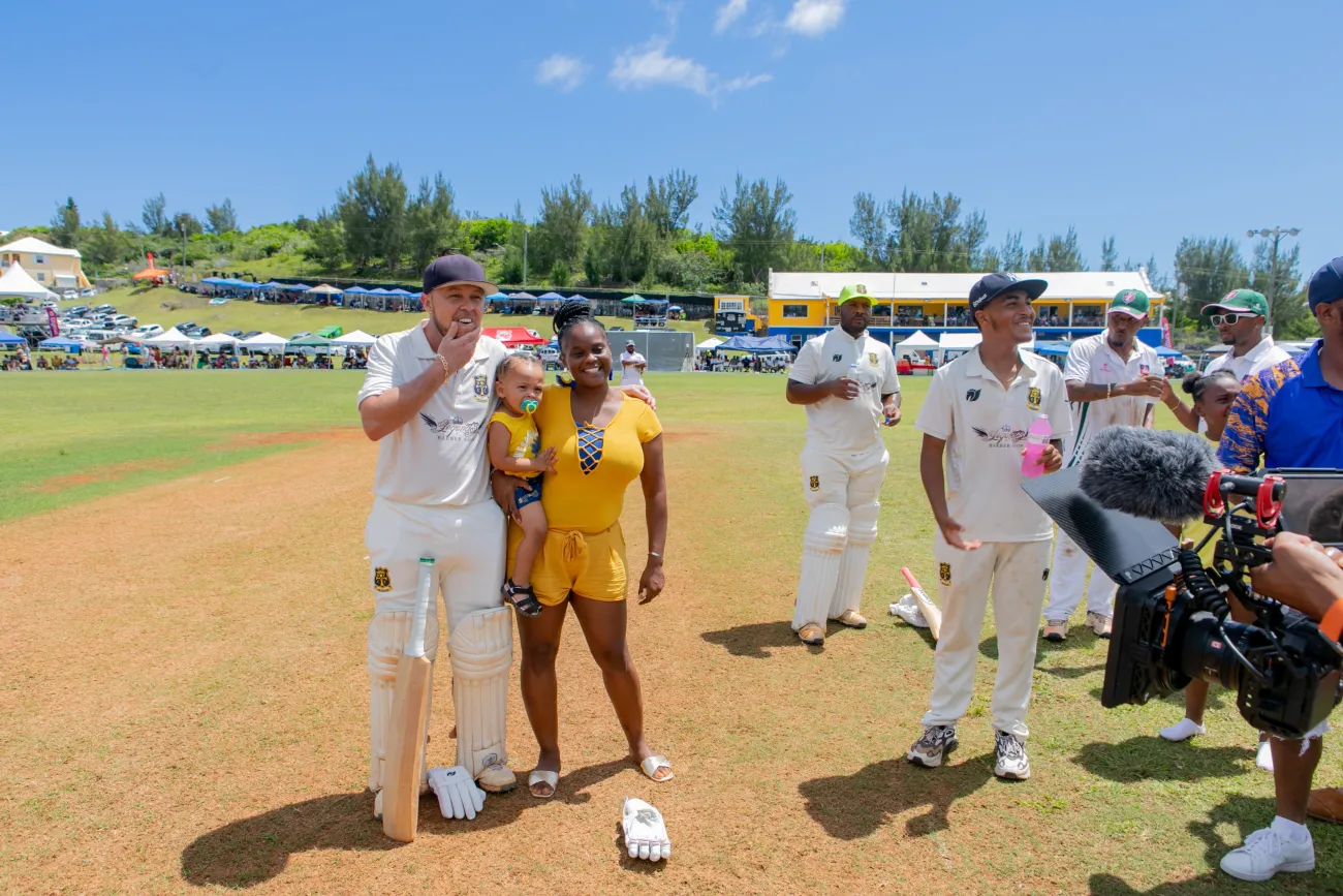 A woman and her child is posing with a cricket player at County Games.