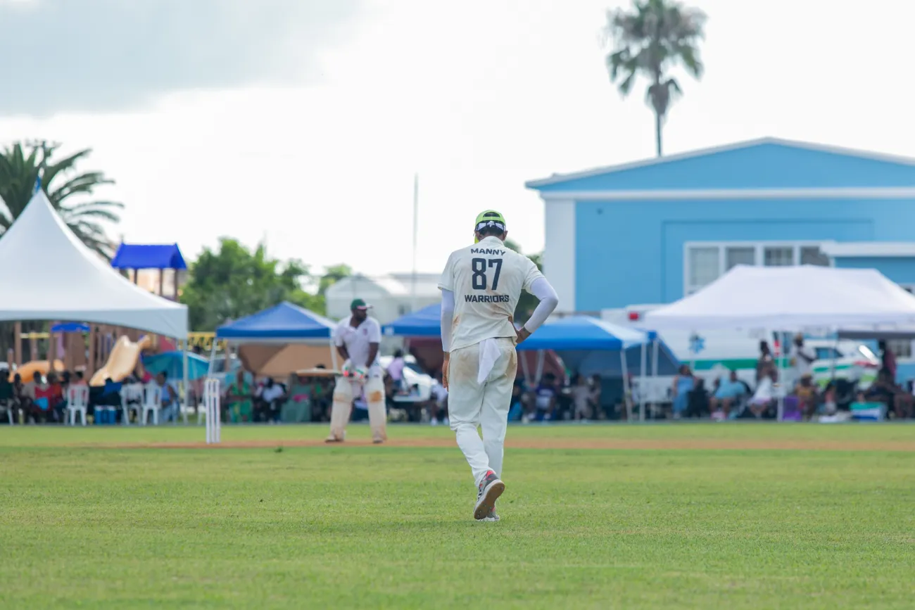 A man is on the field of a cricket pitch.