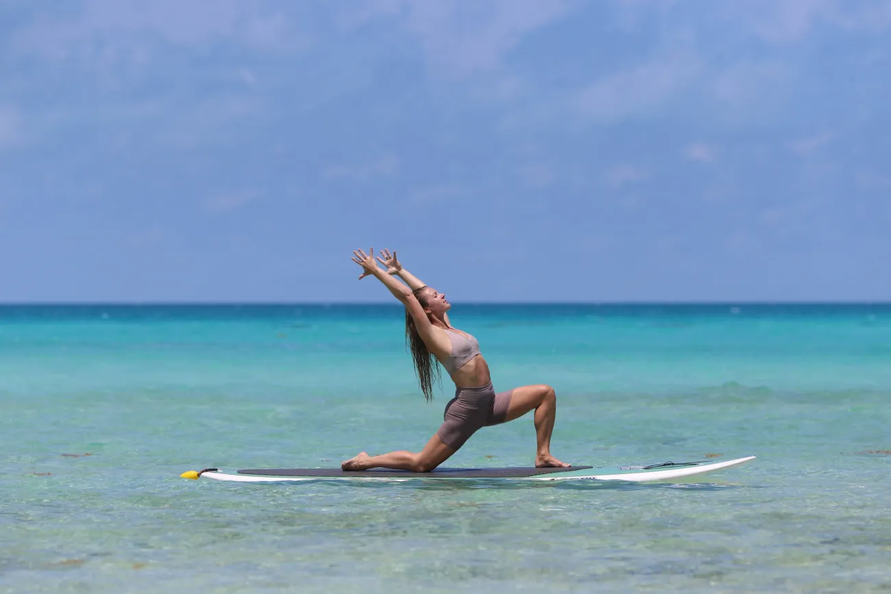 A woman is doing a yoga pose on a paddleboard.