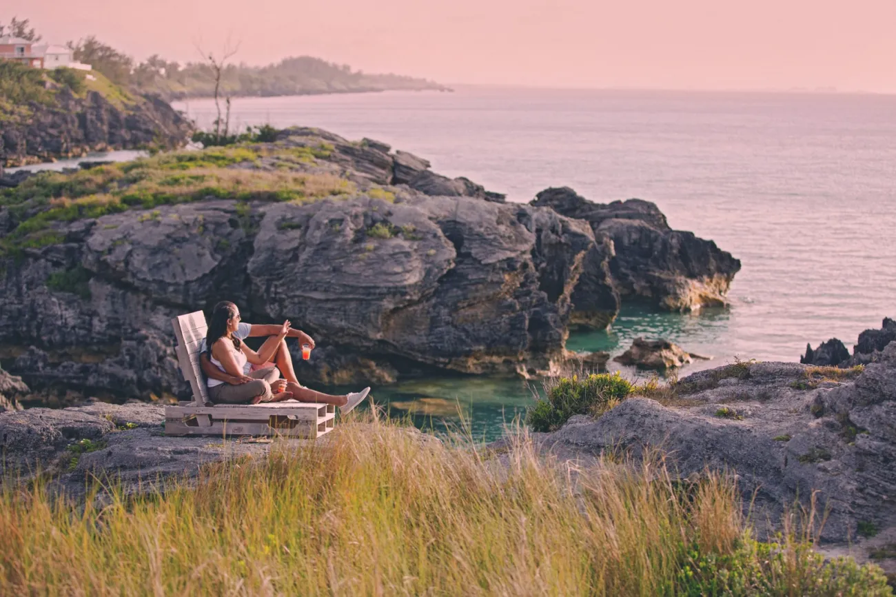 A couple is sitting with a rum swizzle at sunset.