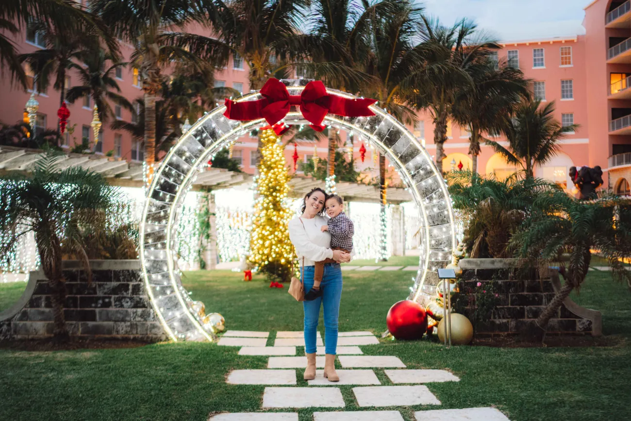 A mother and son are posing under a moongate.