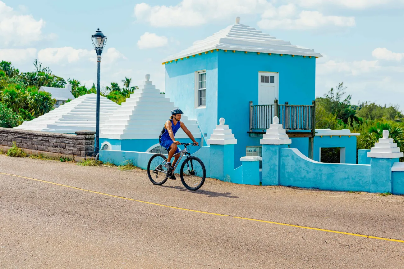 A man is riding a bike next to a blue pastel building.