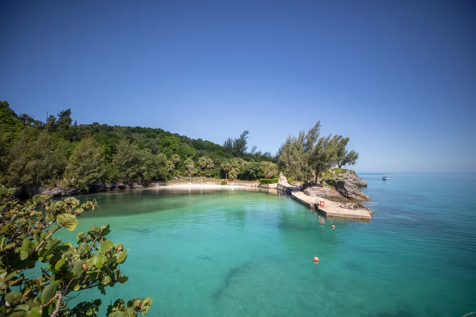 a view of a nearly empty pristine beach with calm waters and a boat in the distance.