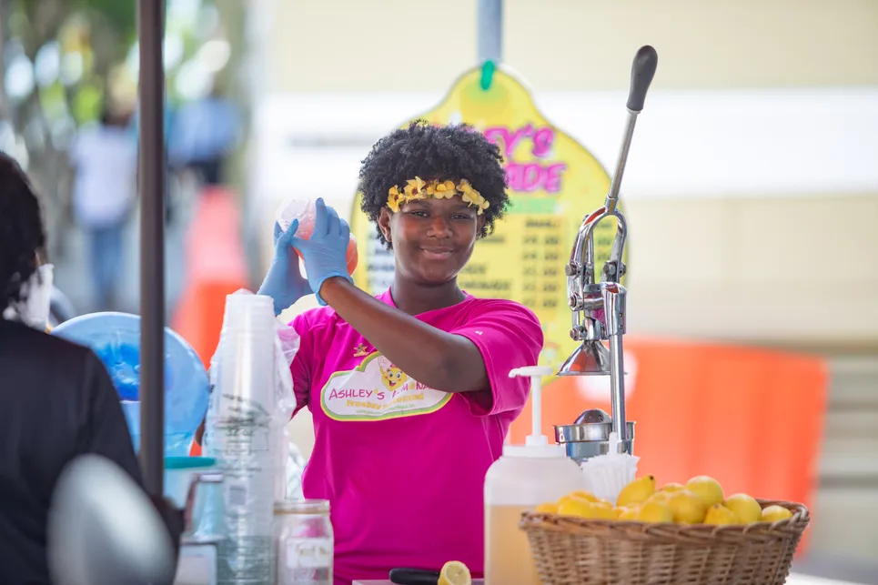 A girl is smiling at the camera making lemonade.