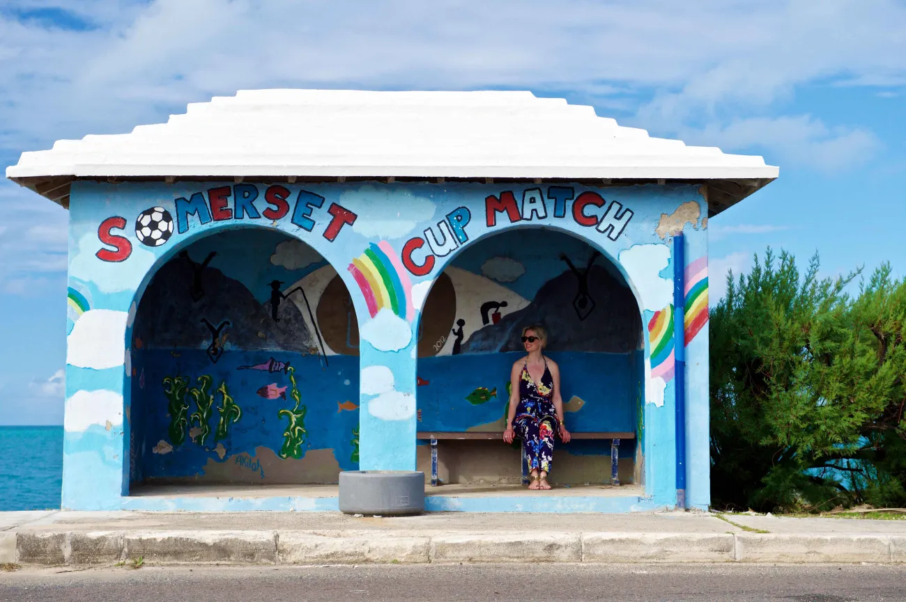 A woman is sitting a bus shelter.