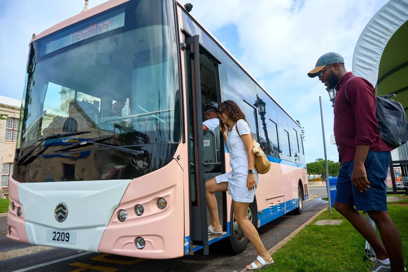 A man and a woman are hoping on an electric bus.