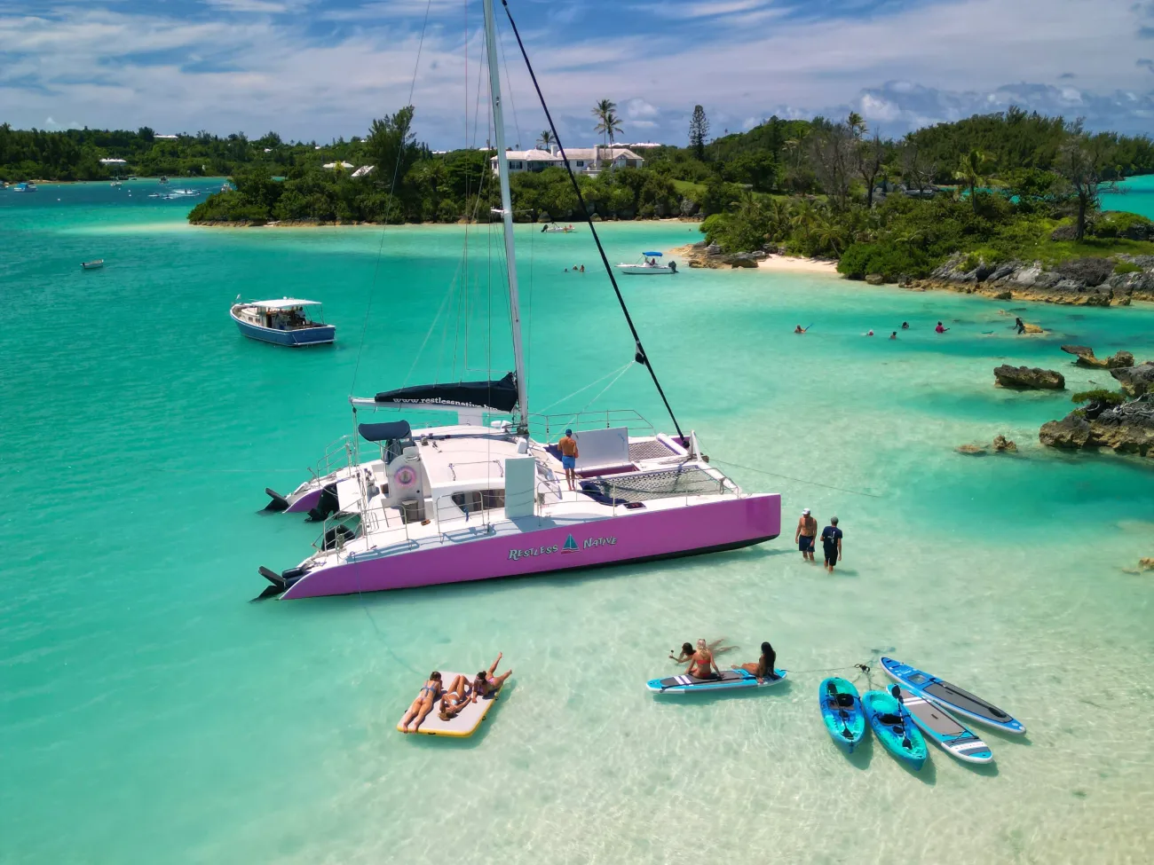 A group of people are relaxing by a catamaran