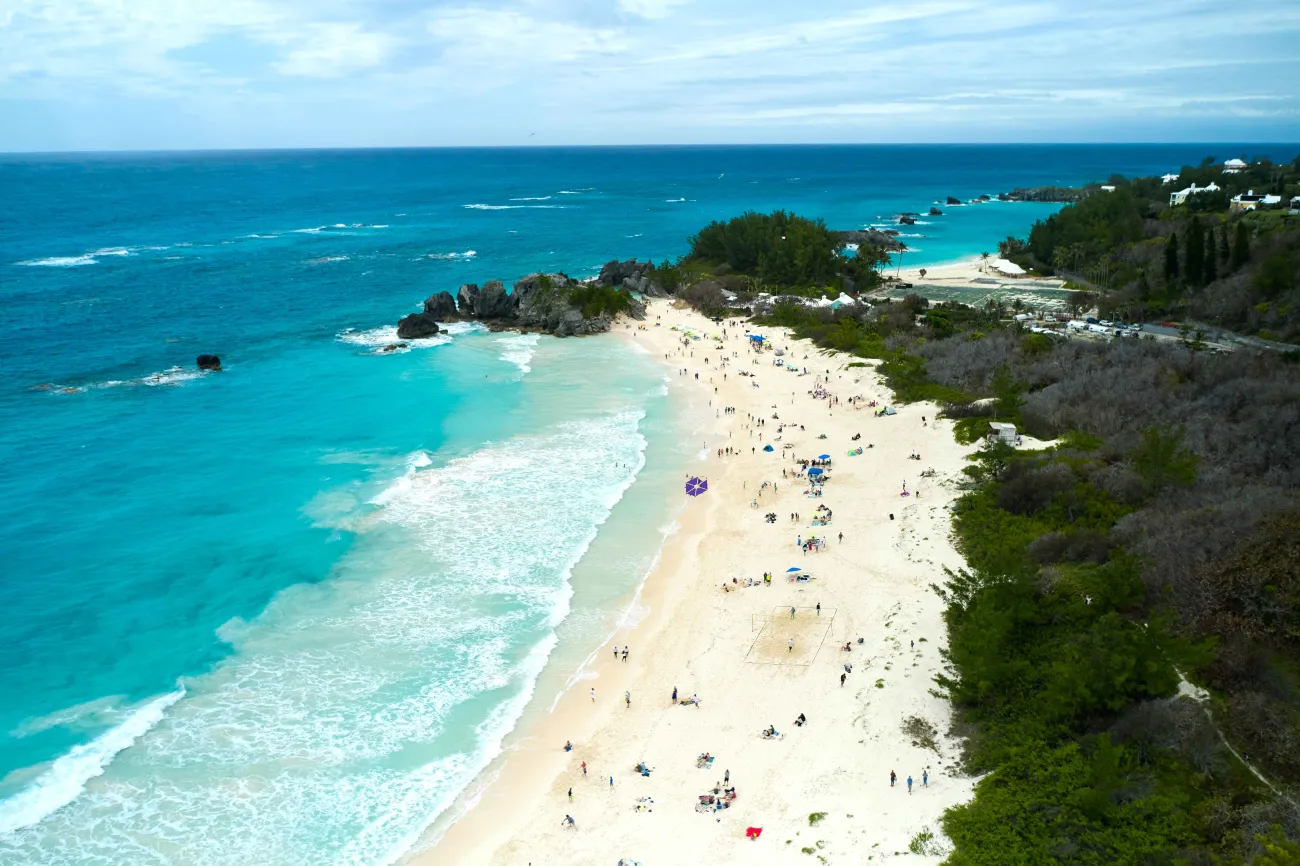 A beach is filled with people flying kites.
