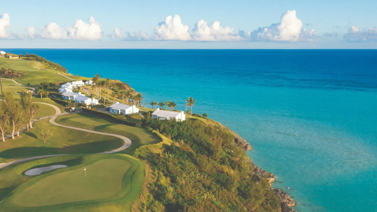 An aerial view of Port Royal Golf Course with a green fairway and blue, calm ocean. 