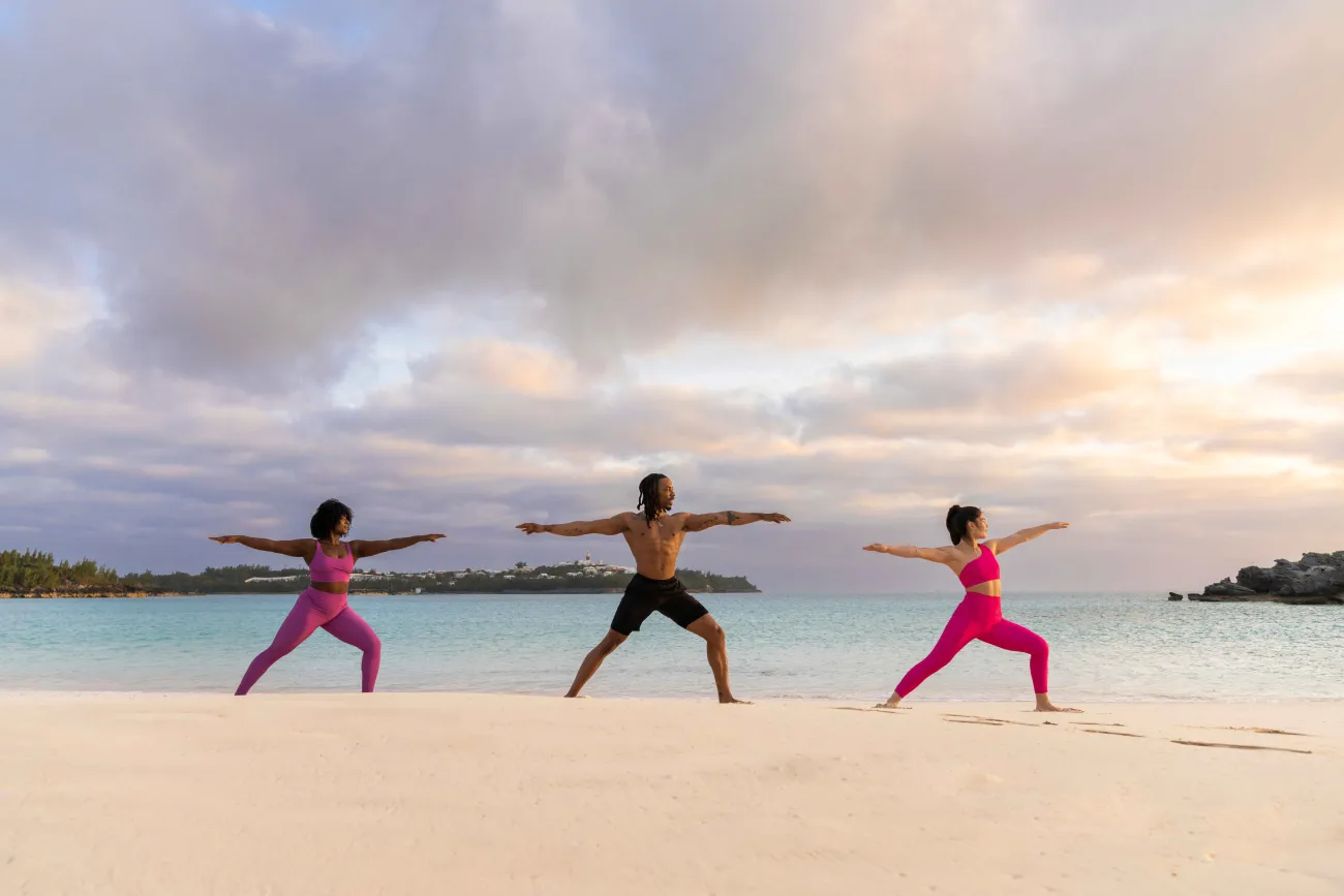 A group of friends are doing yoga on the beach.