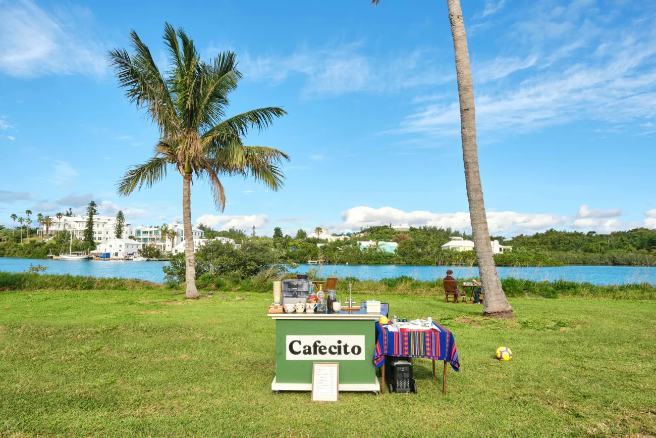 An outdoor coffee stand called Cafecito with a water view and seats in the background.