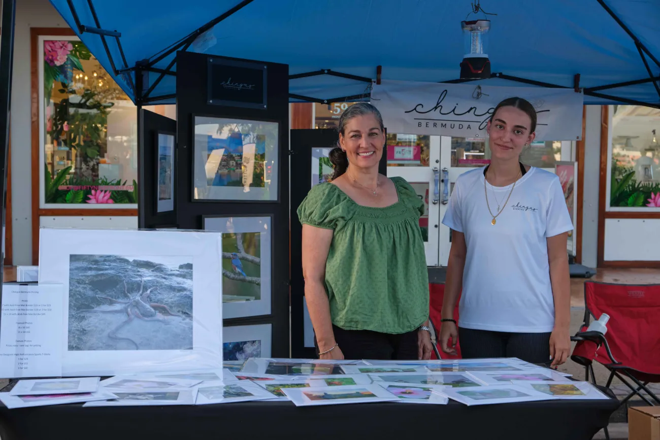 Two woman are smiling at the camera while at their photography booth.