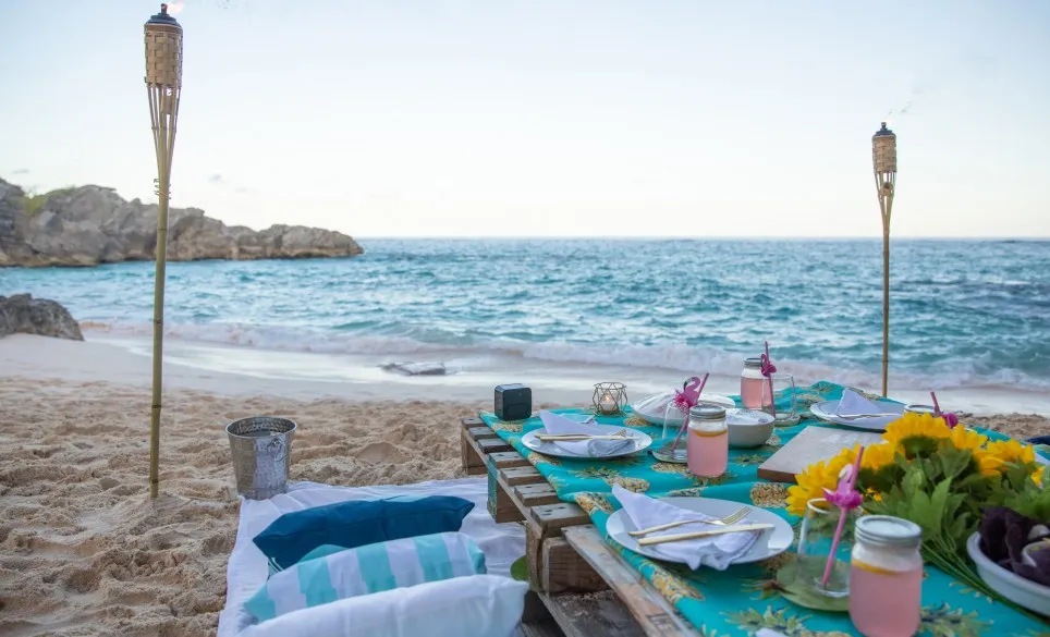 A luxe picnic table set up on the beach at dusk.