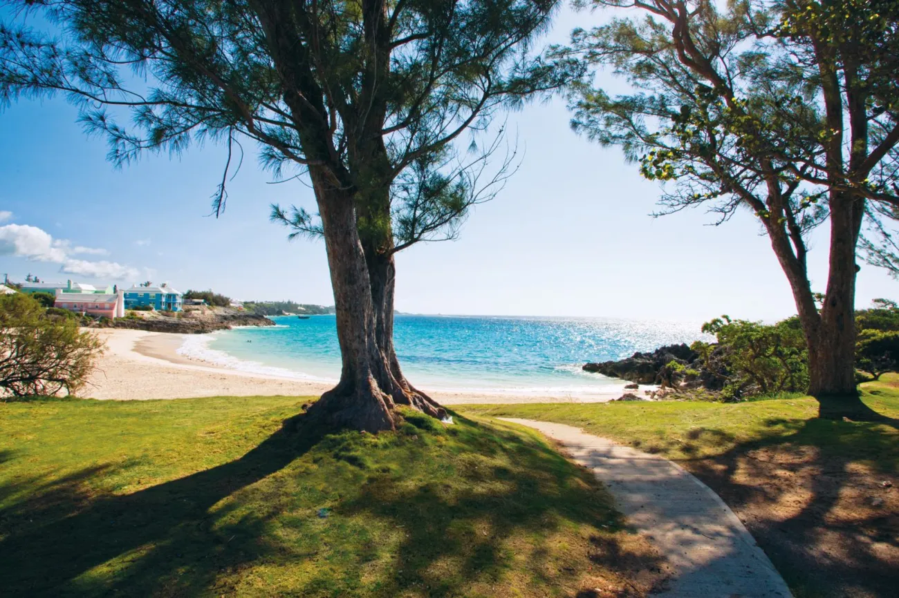 A view of path leading to an empty beach with houses in the back.