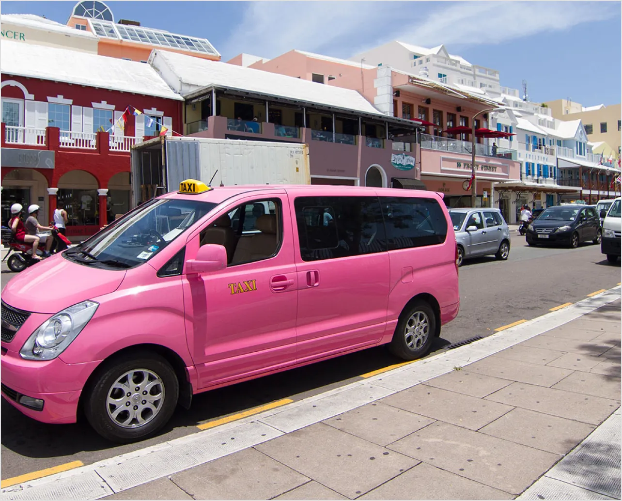 A pink taxi van parked on the side of a road.